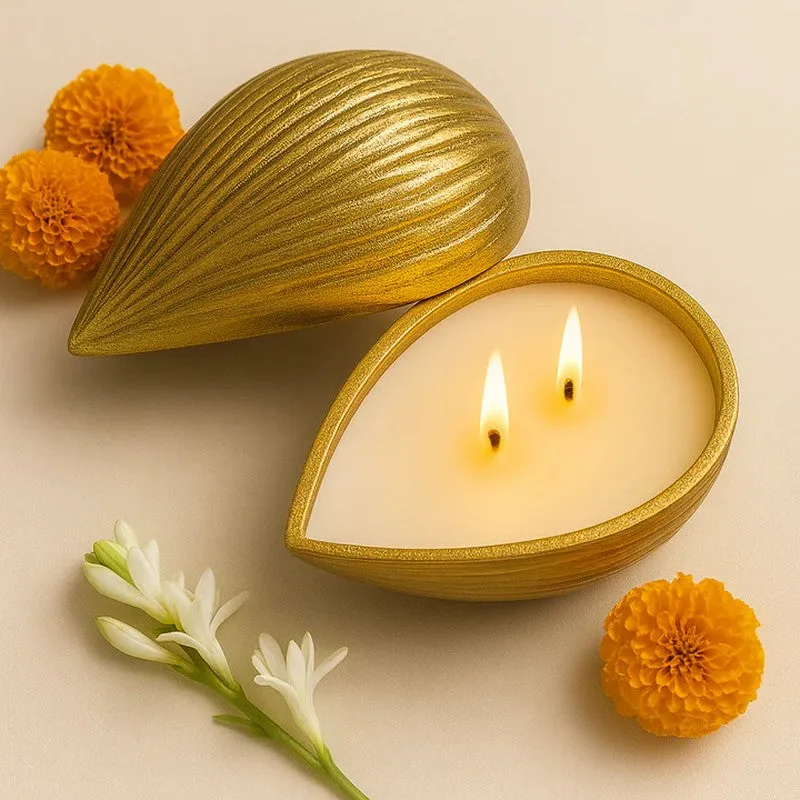 Open golden candle with lid and white flowers in a warm setting