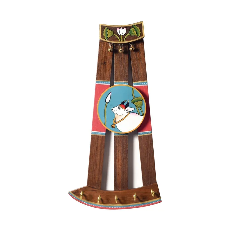 Decorative wooden wall hook with cattle artwork, keys and accessories displayed on hooks.