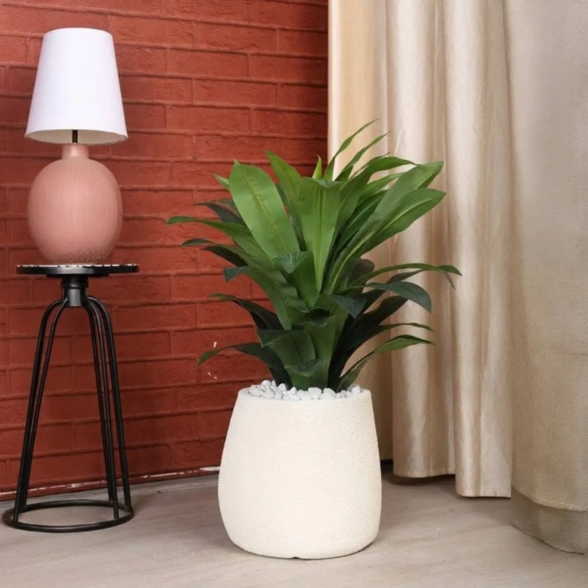 White planter with a leafy plant beside a lamp and curtains