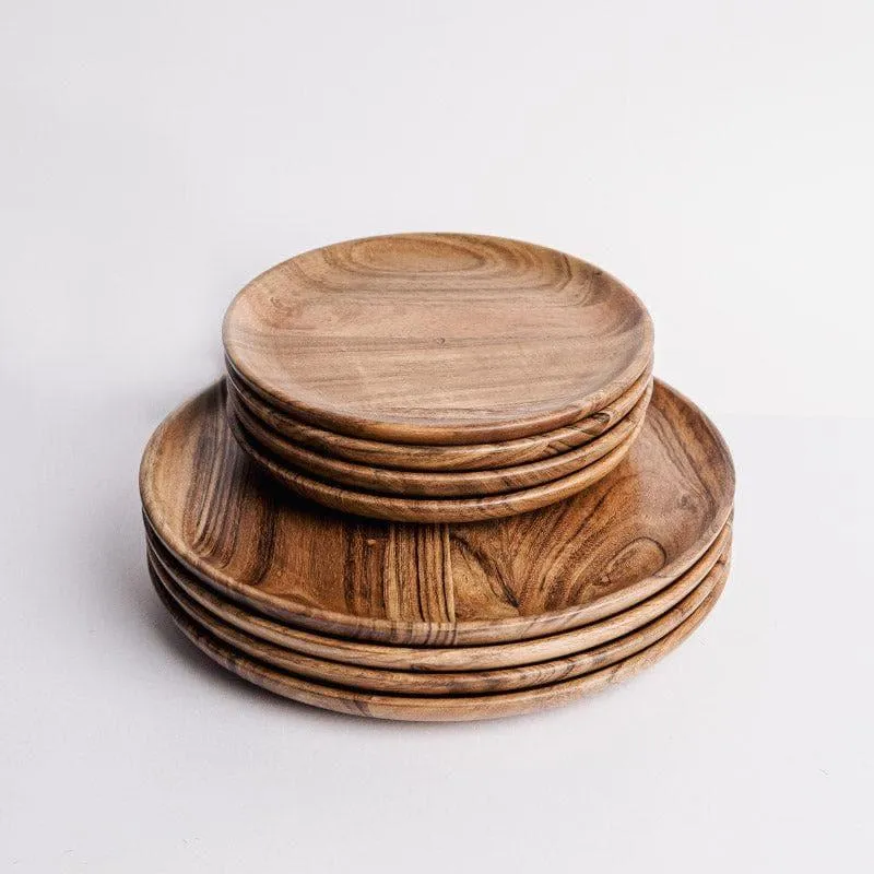 Stacked round brown wooden dinner and quarter plates against a light background