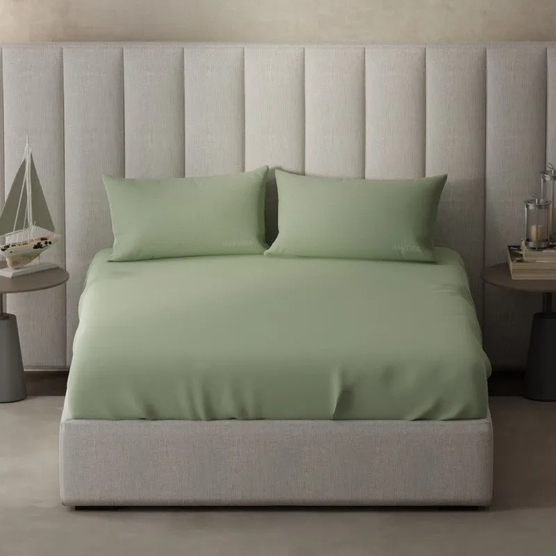 King bed dressed in a solid olive green bedsheet and pillows