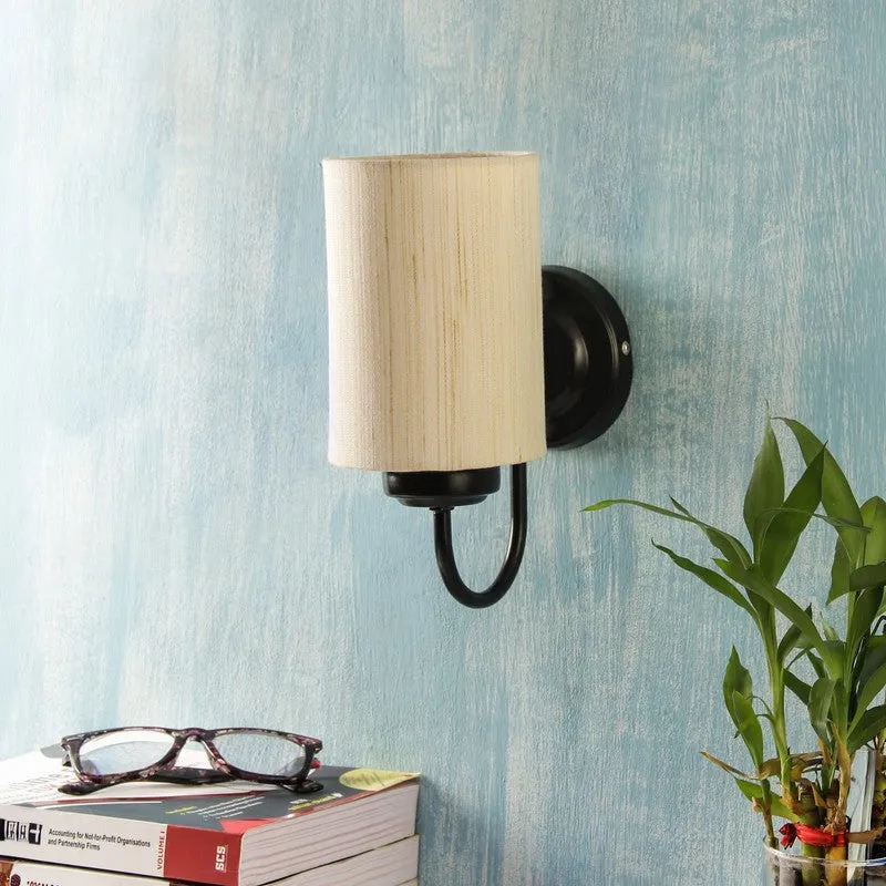 Unlit beige cylindrical wall lamp with black iron base on a blue wall