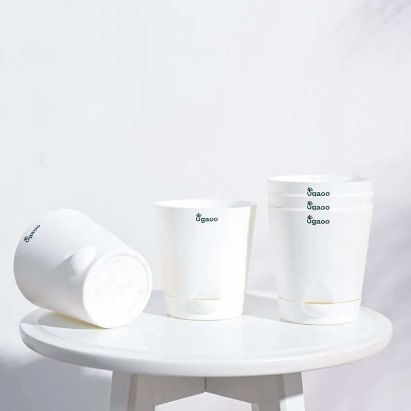 Four white planters arranged on a round white table