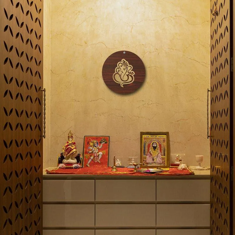 Round brown wall accent with a gold Ganesha motif displayed above a home shrine