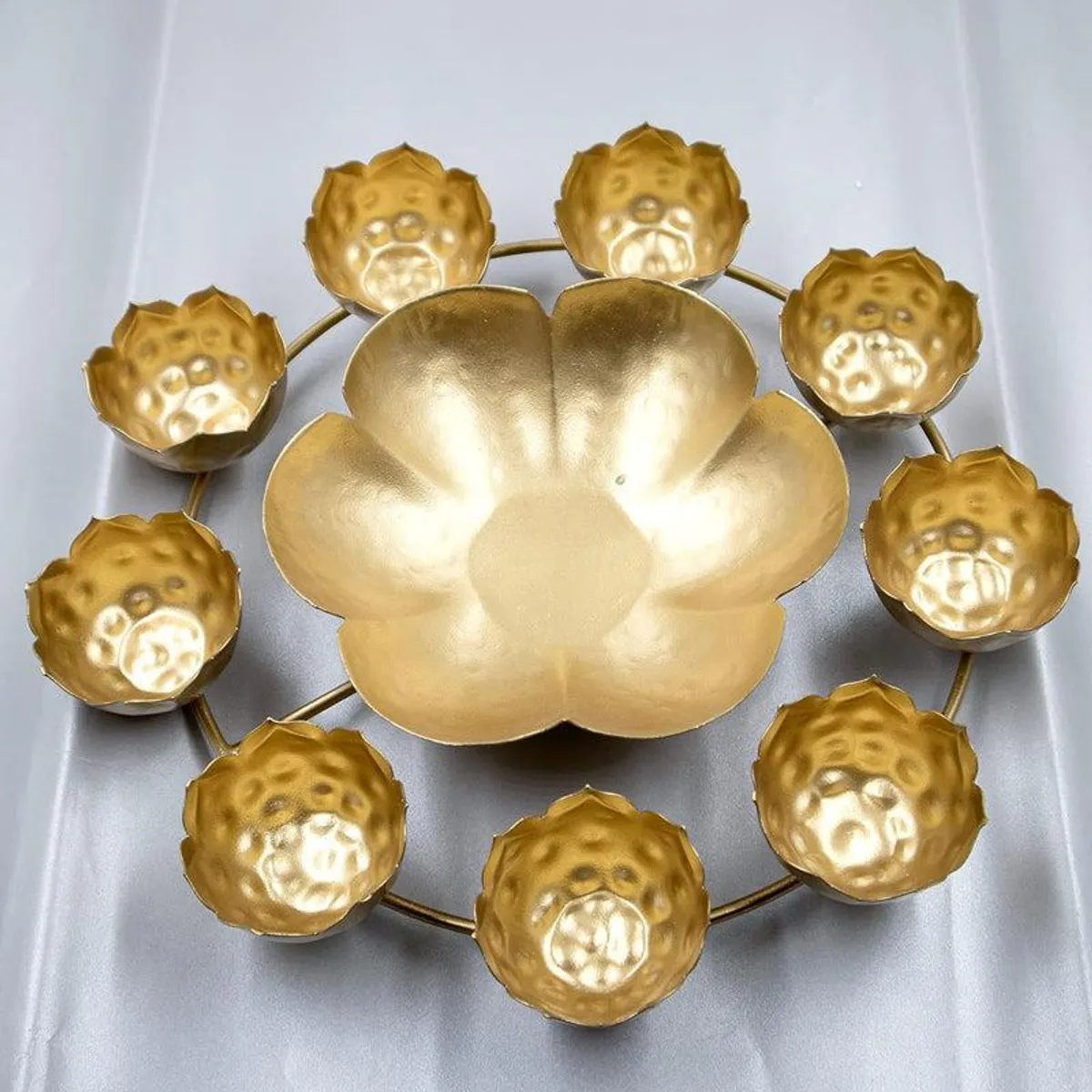 Gold flower-shaped urli with surrounding diya holders, top view