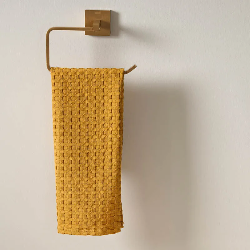 Close view of a yellow waffle hand towel on a brass rail