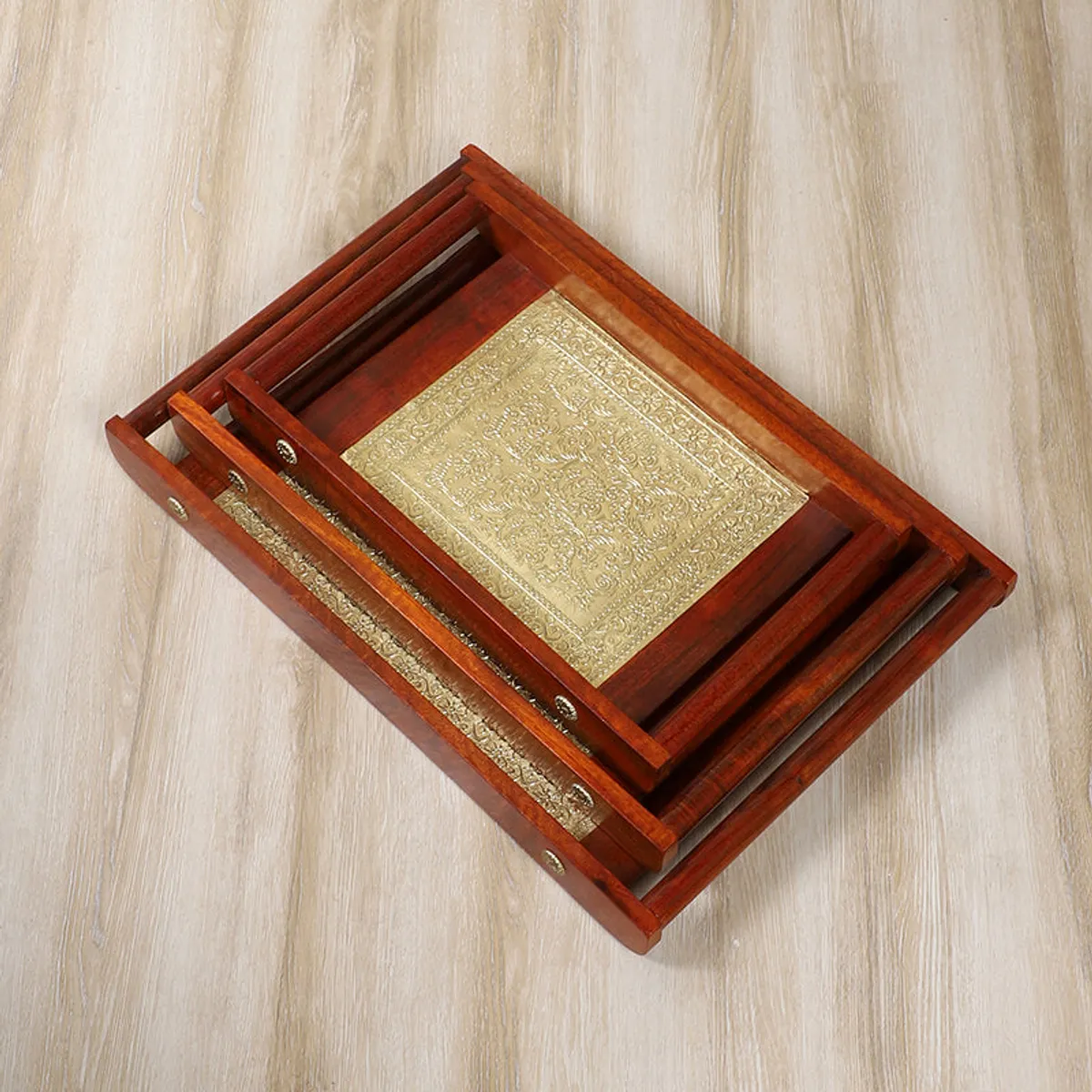 Stacked brown wooden serving trays showing their ornate gold inset panels