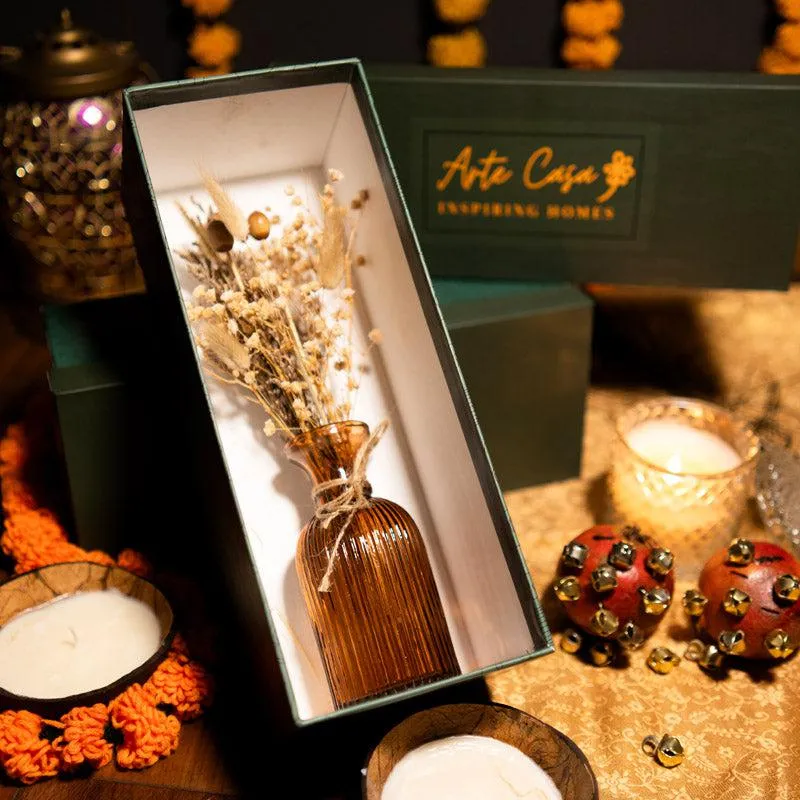 Dried floral arrangement and amber vase presented inside a dark green gift box
