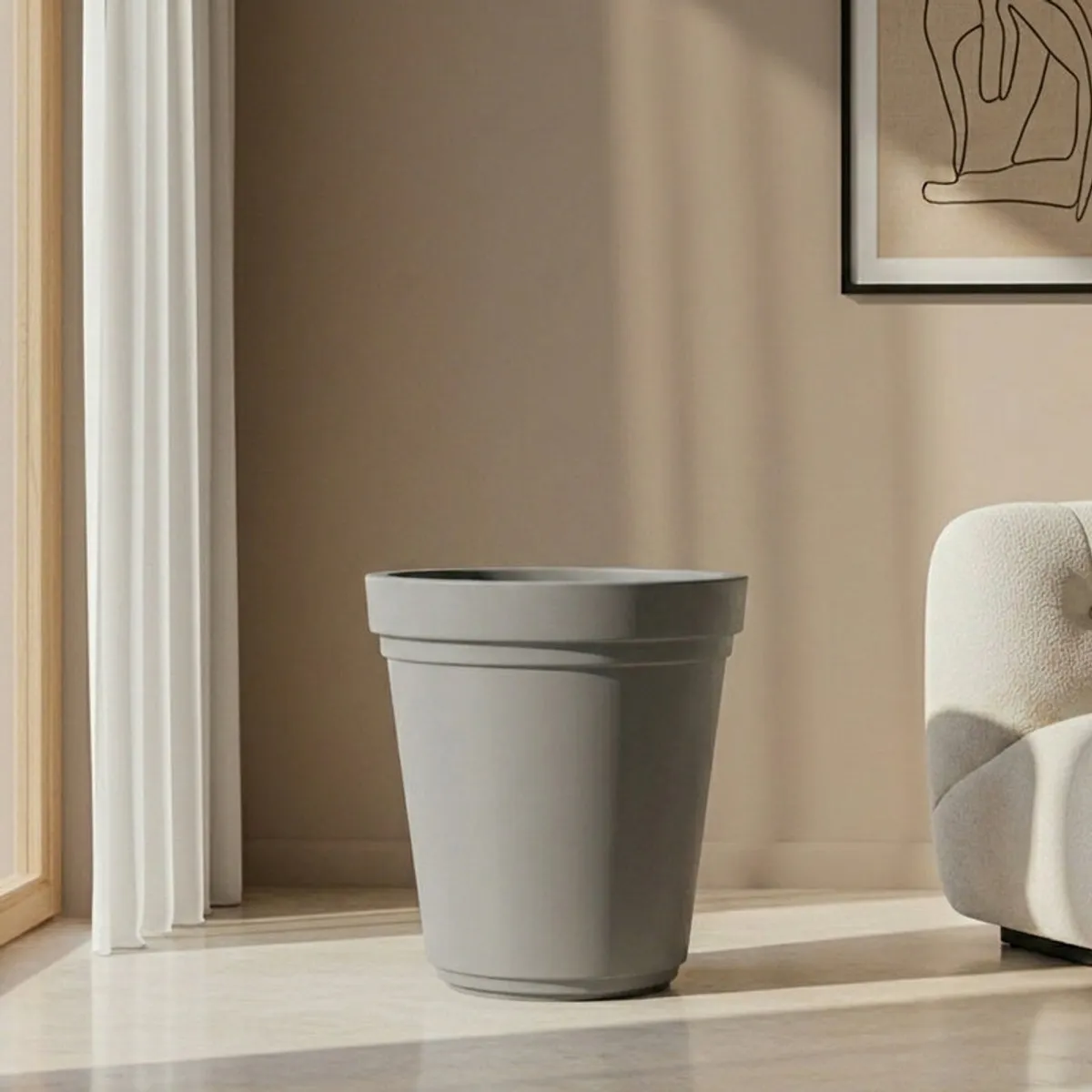 Empty grey cylindrical planter with a wide rim beside a neutral lounge chair.