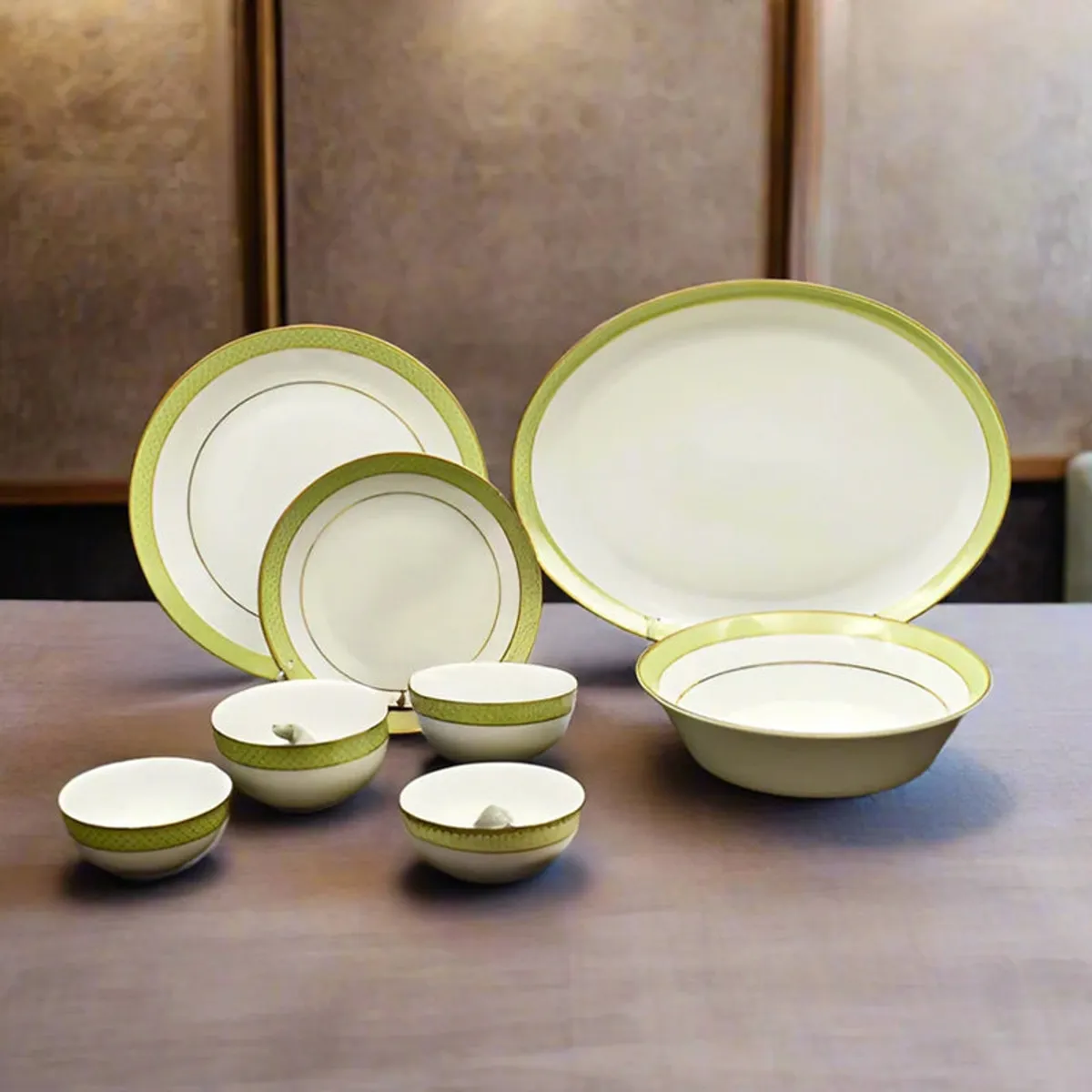 White and green porcelain dinner set with gold accents arranged on a dining table