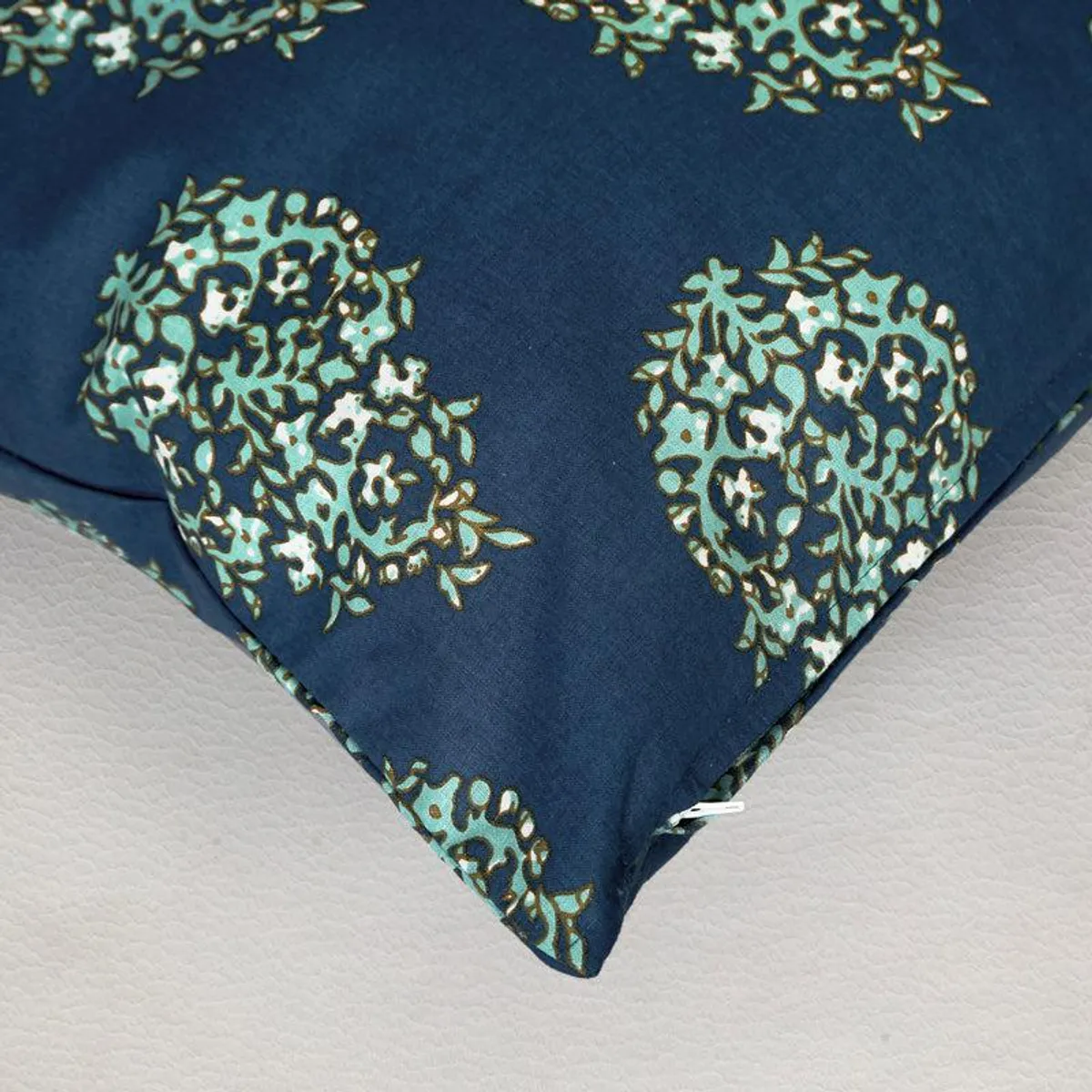 Close-up of a blue cushion cover corner showing printed motif and zip opening