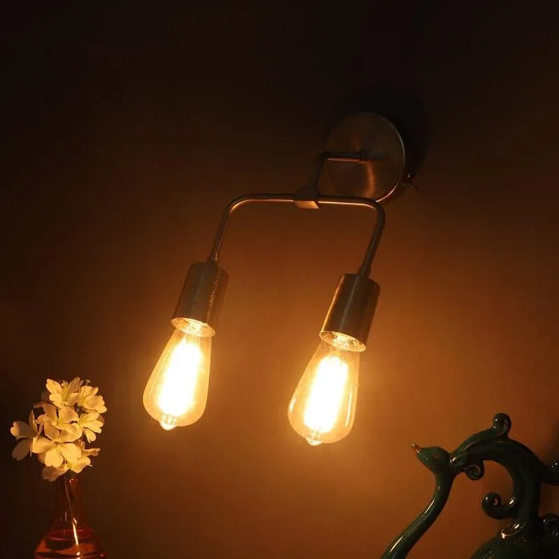 Silver wall lamp with two clear glass shades glowing in a warm setting