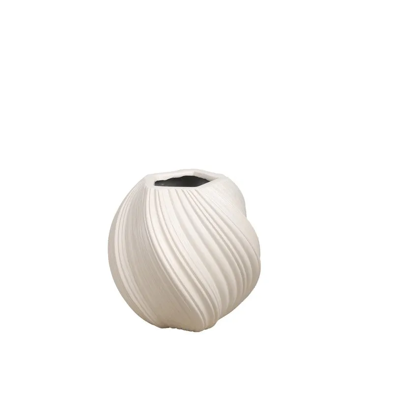 White round ribbed planter with a green plant beside a brick wall