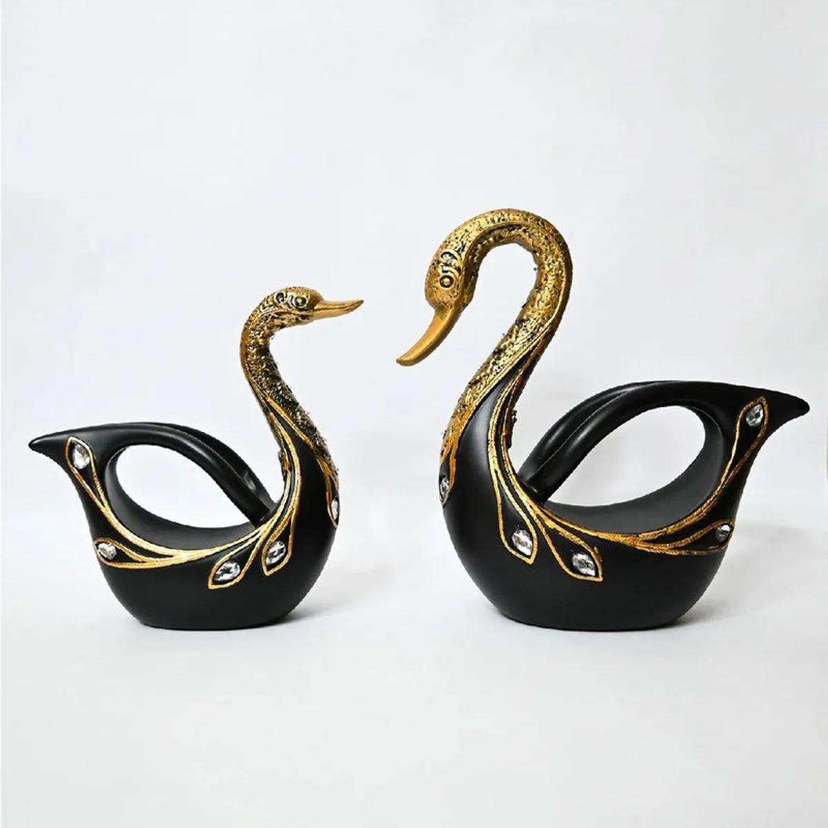 Front view of two black and gold swan showpieces displayed side by side.