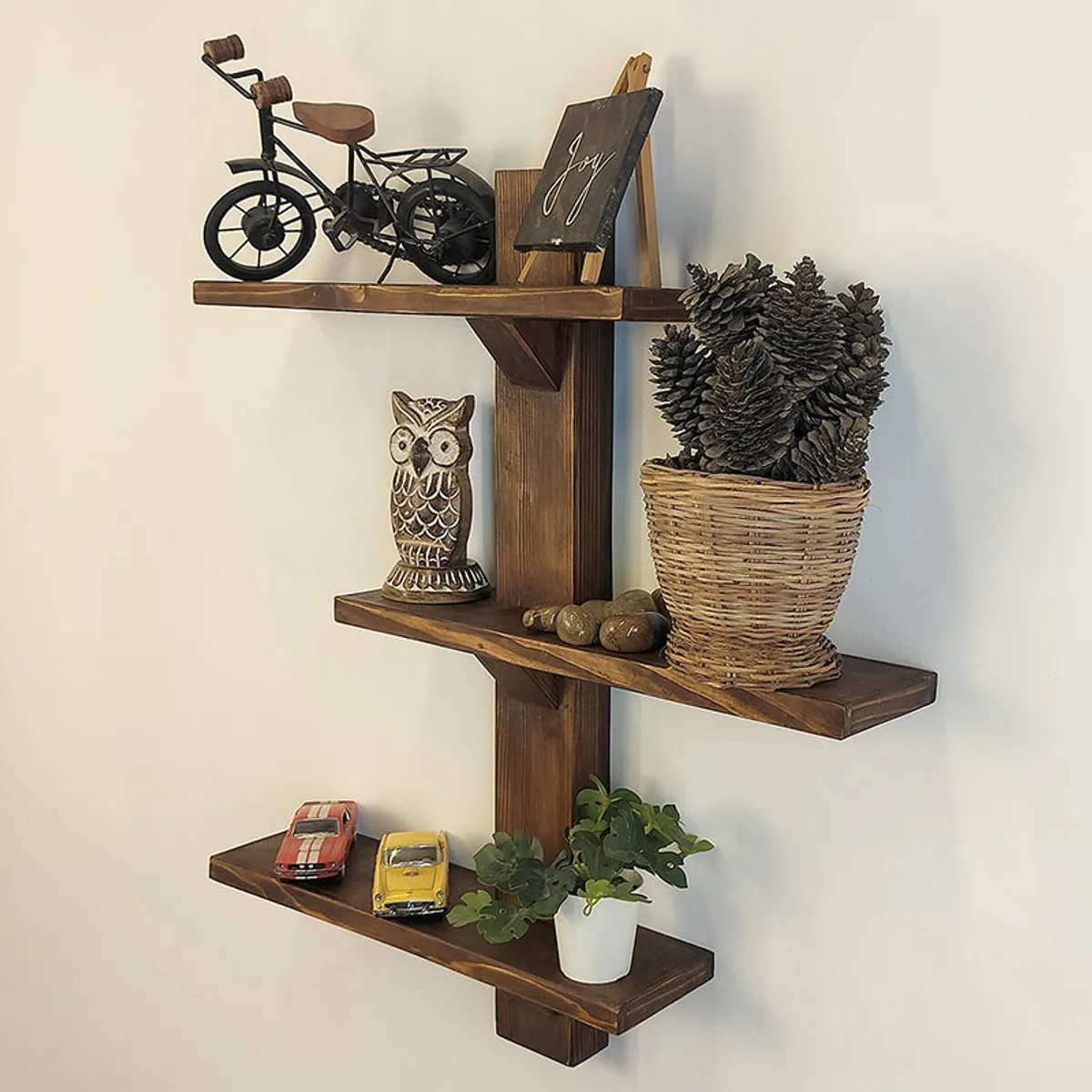 Brown wooden wall shelf organiser with three tiers styled with decor and plants.