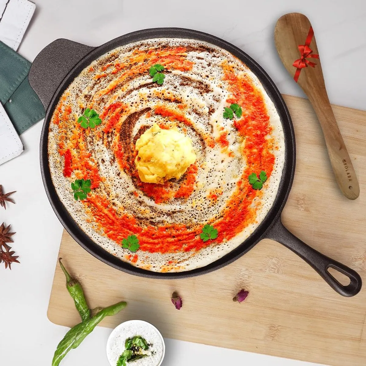 Top view of a black cast iron dosa tawa with handle and a dosa