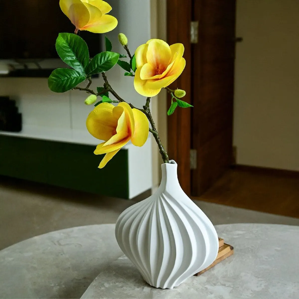 White sculptural vase with yellow flowers on a coffee table