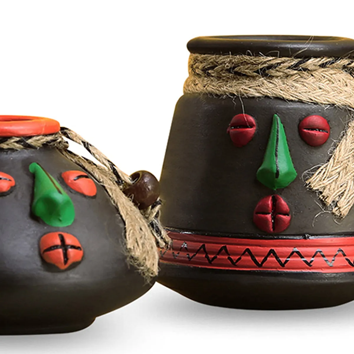 Close-up of black terracotta face vases with tribal-inspired painted details