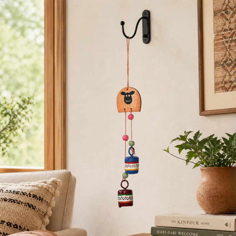 Sheep-face windchime hanging on an indoor wall beside a plant