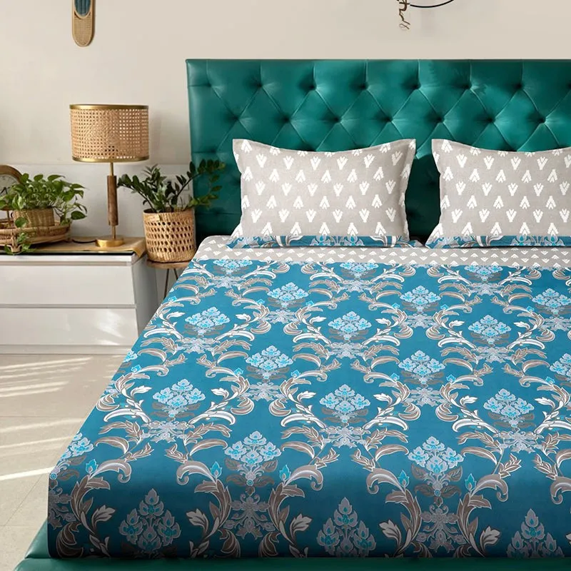 Close view of blue patterned bedsheet with grey pillow covers on a tufted teal headboard
