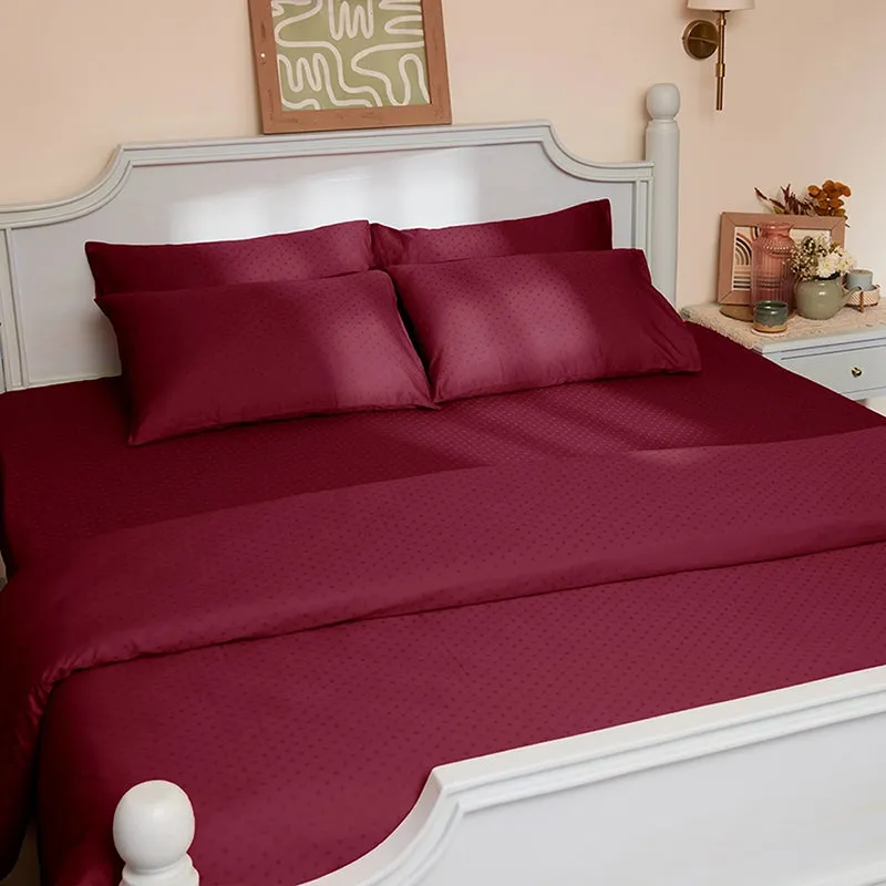 Maroon geometric self-design duvet cover styled on a classic white bed