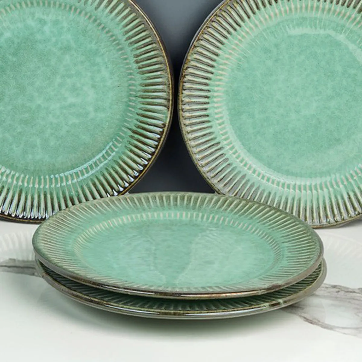 Close view of stacked green ceramic plates with radiating textured rims.