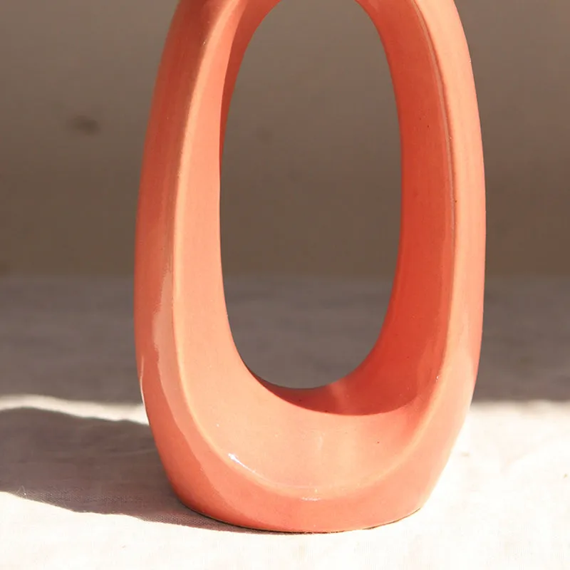 Close-up of the lower half of a pink ceramic donut vase