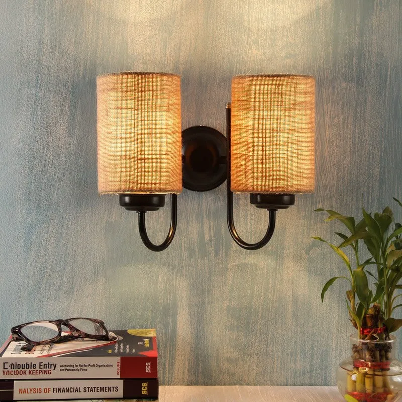 Lit dual jute wall lamp with black iron frame against a blue wall