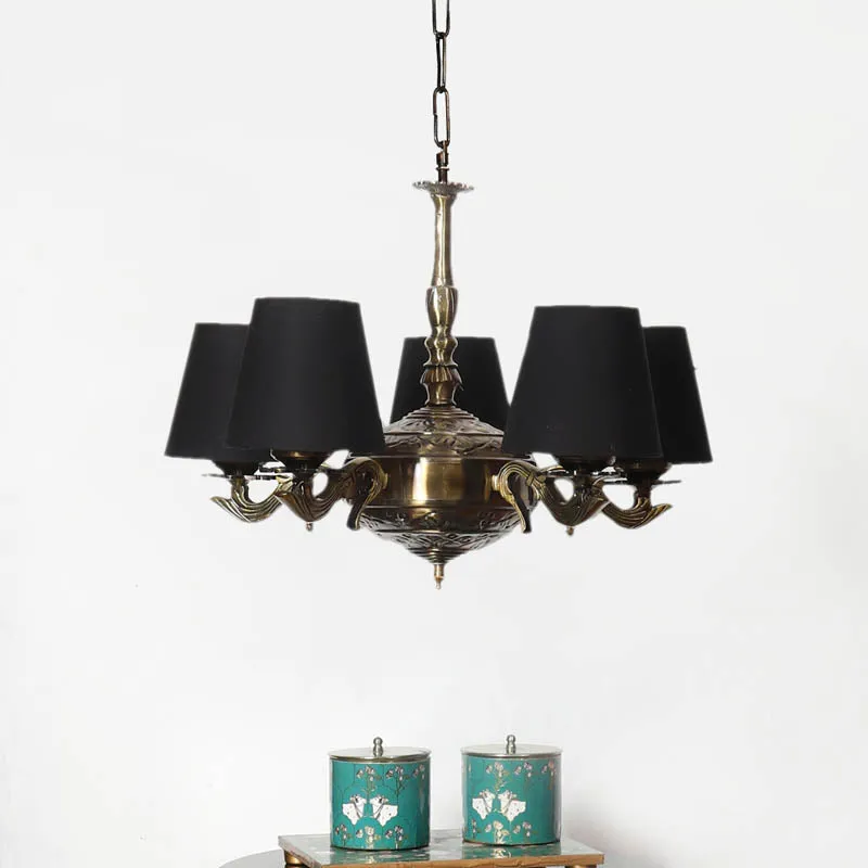 Golden antique ceiling lamp with black conical shades hanging above a console