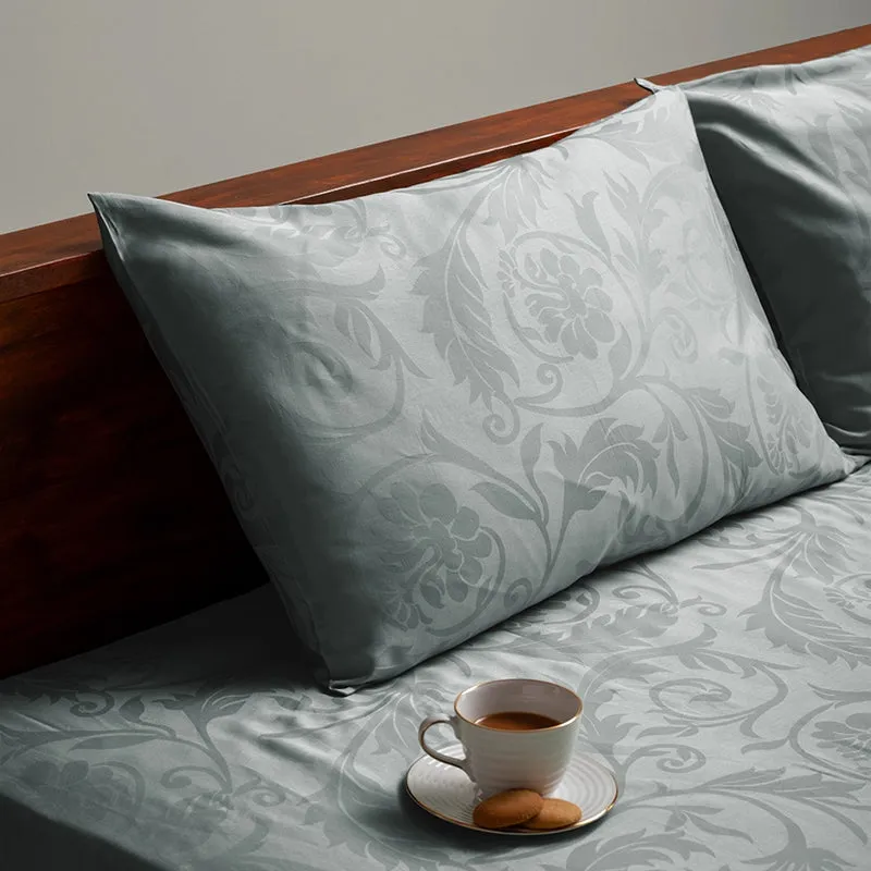 Light grey floral duvet cover and pillow with a cup of tea on the bed