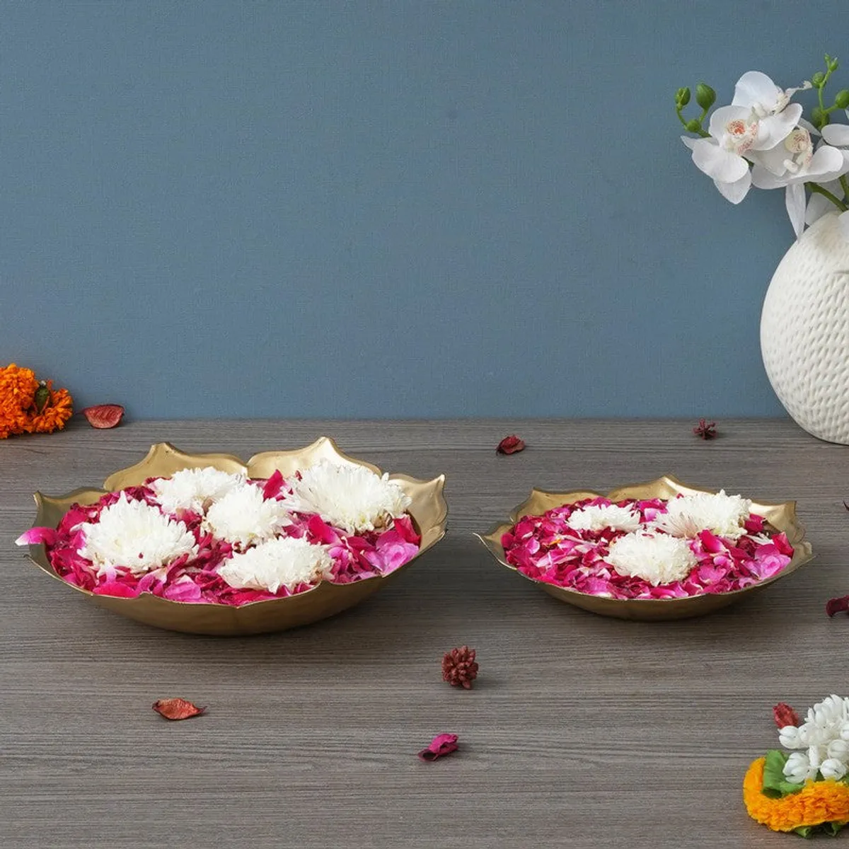 Gold urli set of two styled with petals and flowers on a wooden surface