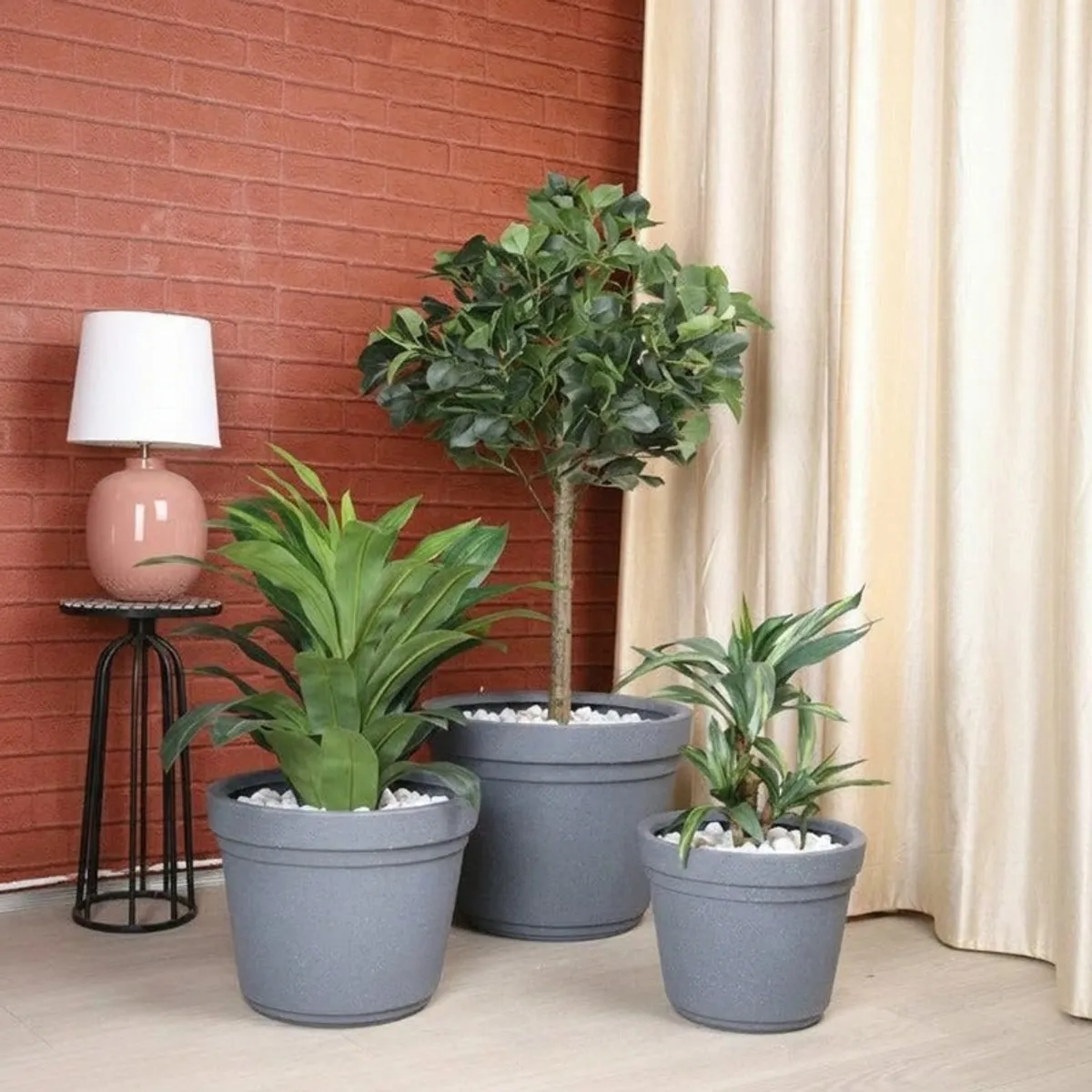 Three grey planters in different sizes styled with green indoor plants.
