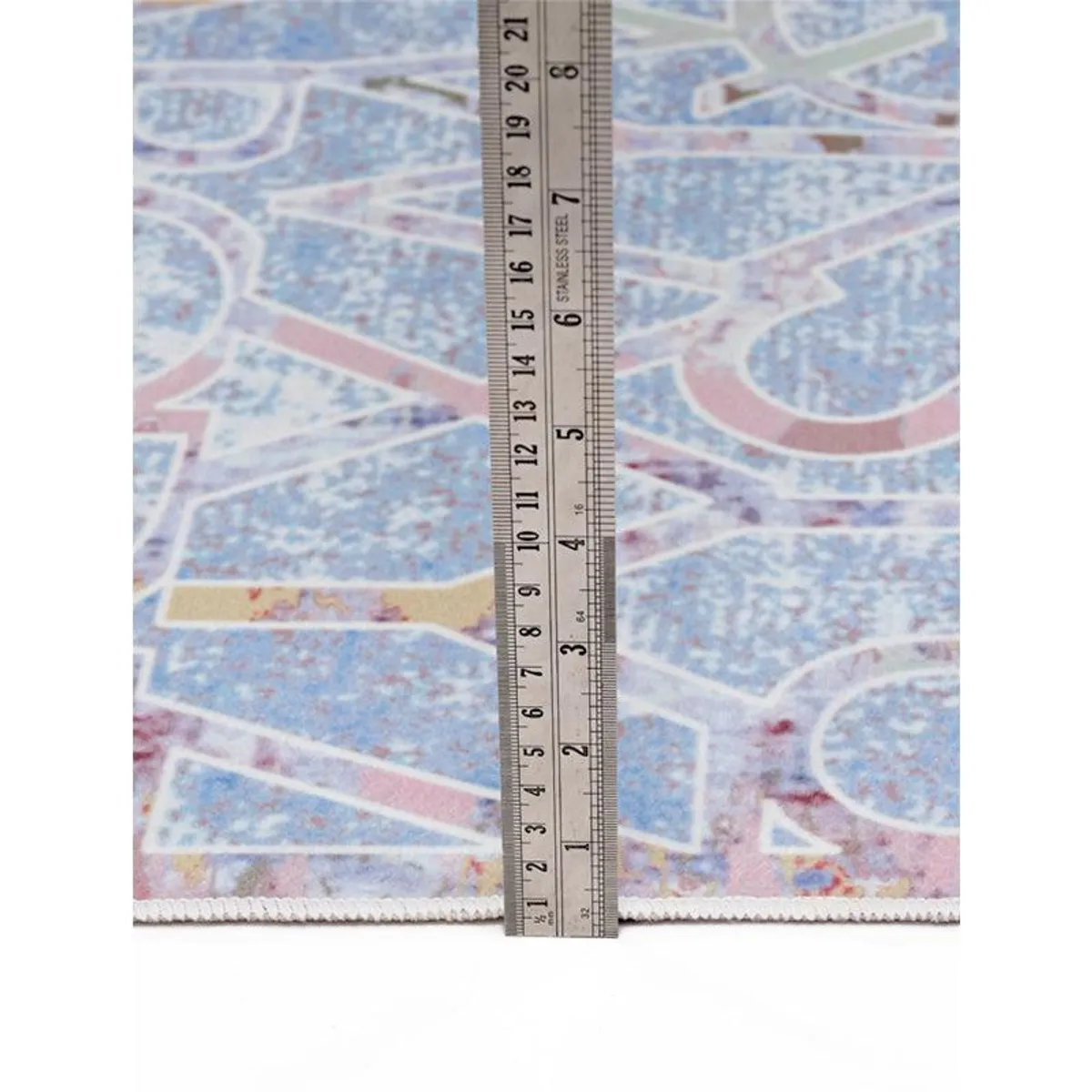 Close-up of the carpet edge with a ruler placed vertically beside it