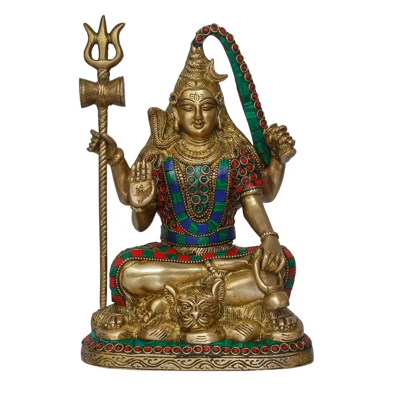 Studio front view of a seated deity idol with trident and coloured details