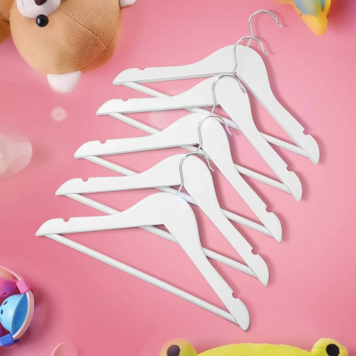 White wooden hangers arranged on a pink surface