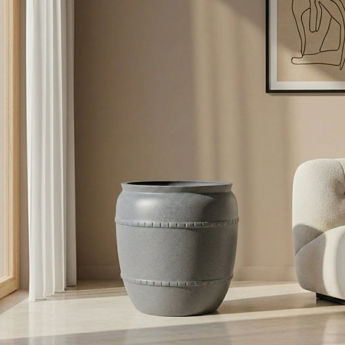 Empty grey rounded planter with a matte speckled finish beside a chair