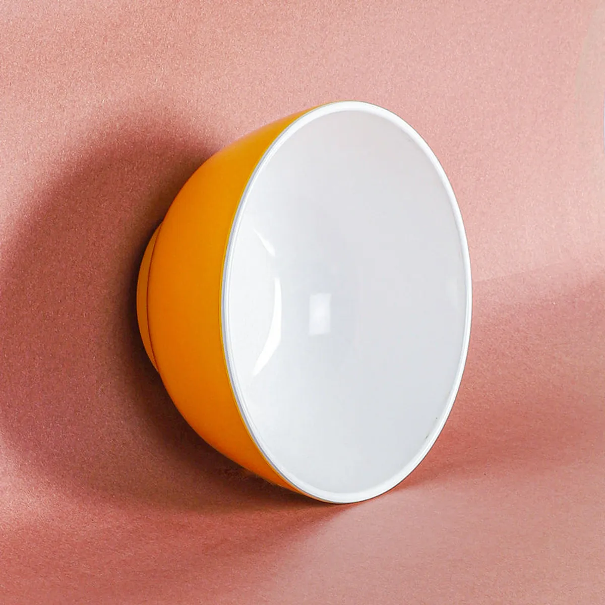 Top view of a yellow and white bowl resting on a pink surface.