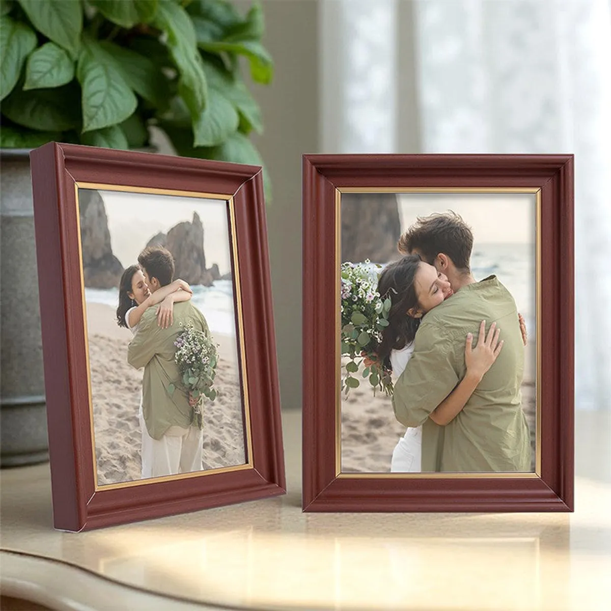 Two brown and gold photo frames shown together beside a leafy plant.