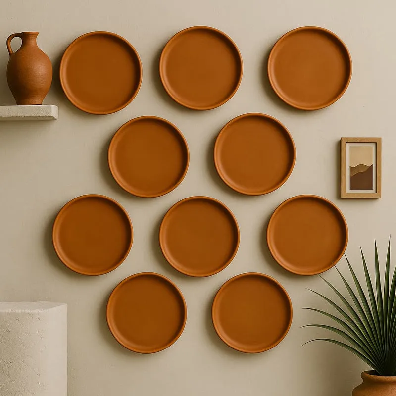 Round brown wall plates arranged among pottery and framed art on a neutral wall