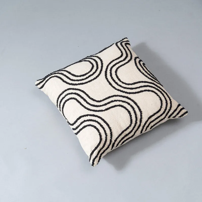 Square ivory cushion cover with black abstract wave pattern on a plain surface