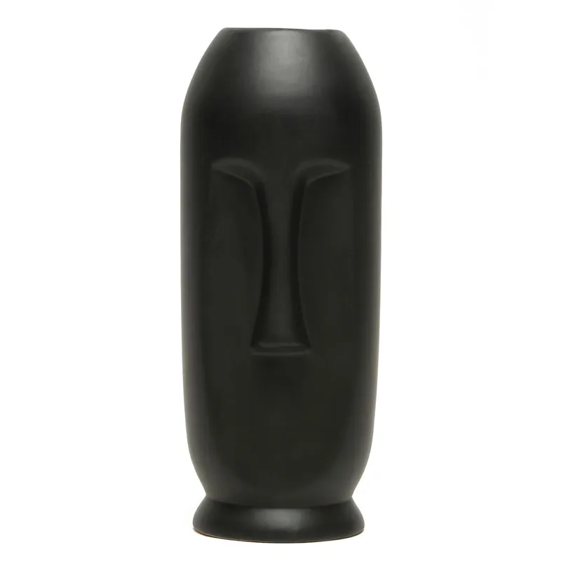 Single tall matte black face vase on a white background.