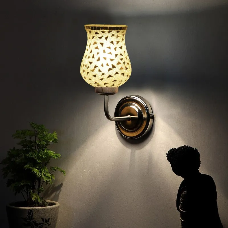 Silver wall lamp with glowing mosaic glass shade in dim setting