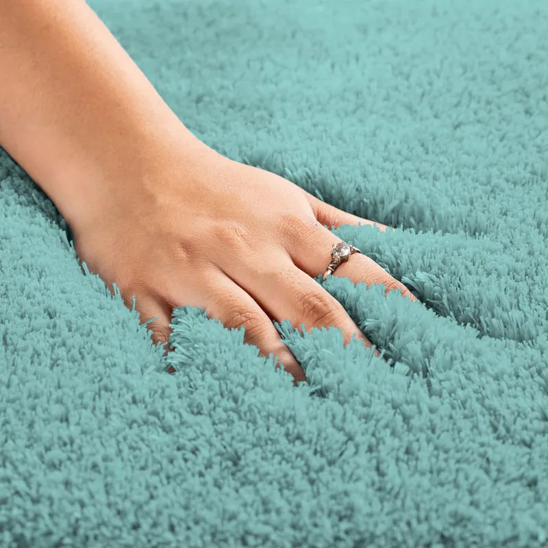 Close-up of a hand pressing into the soft aqua rug pile