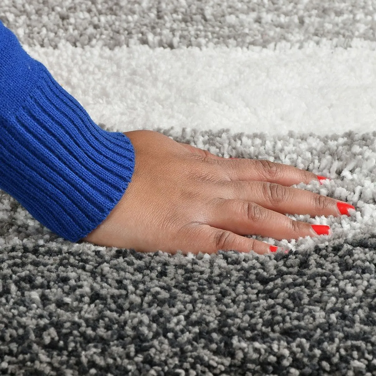 Hand touching the soft, textured surface of the striped bath mat