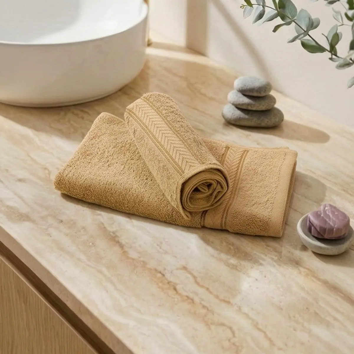 Rolled and folded beige hand towels displayed on a marble bathroom counter