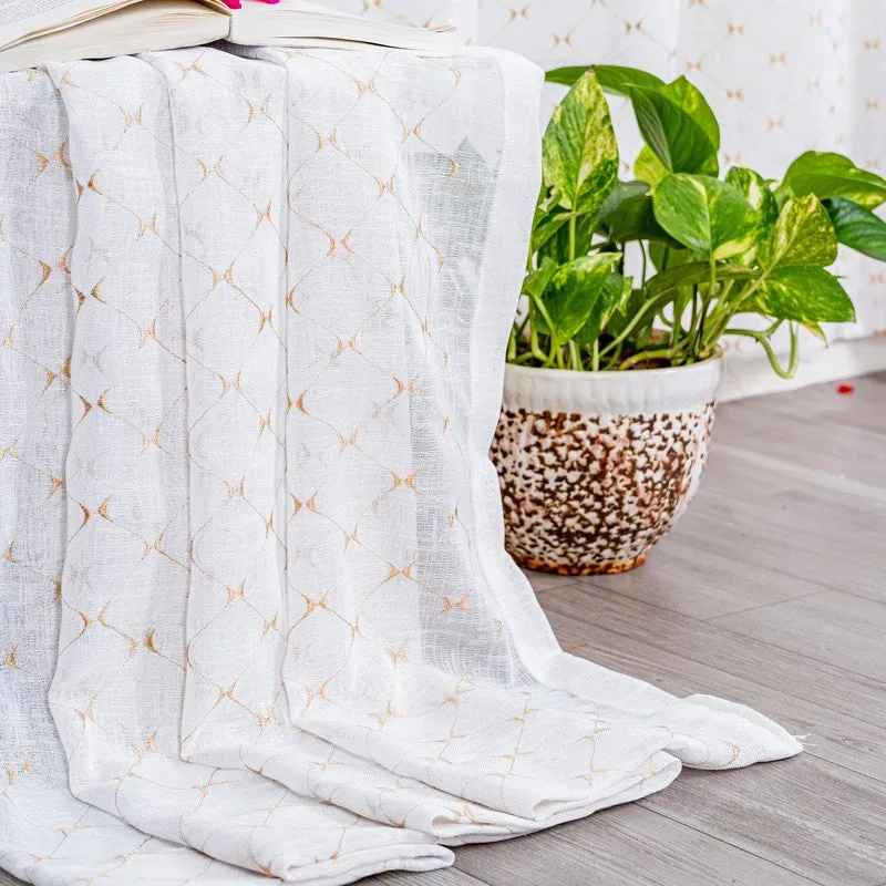 Sheer patterned curtain draped beside a potted plant and stool