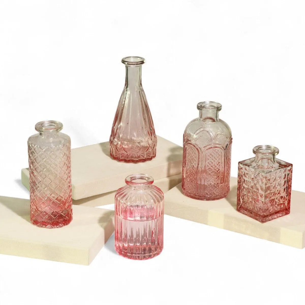 Five pink glass decorative vases arranged on display blocks