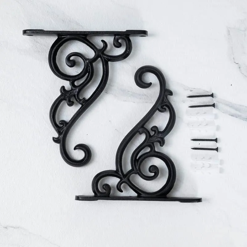 Two black scrolling wall brackets shown with wall plugs and screws on a white surface.