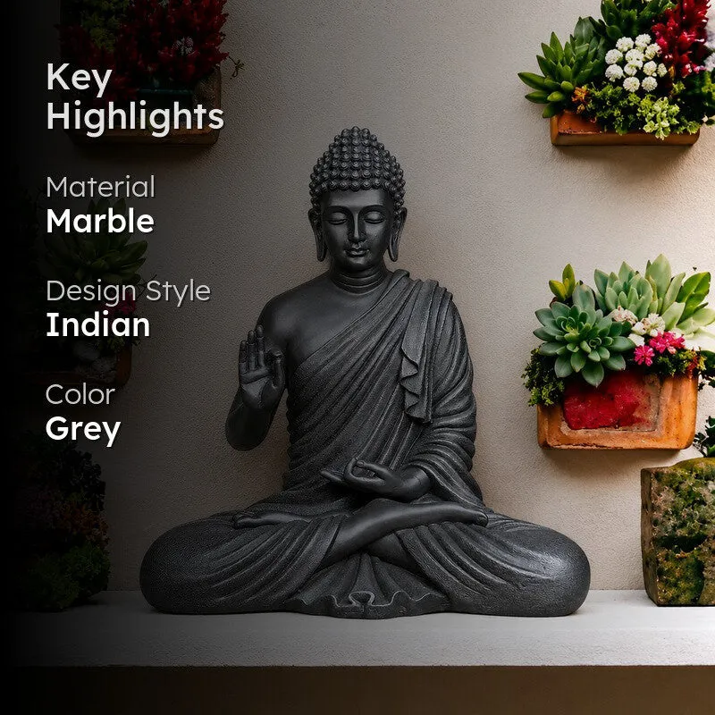 Grey Buddha idol displayed on a shelf in a plant-filled interior setting