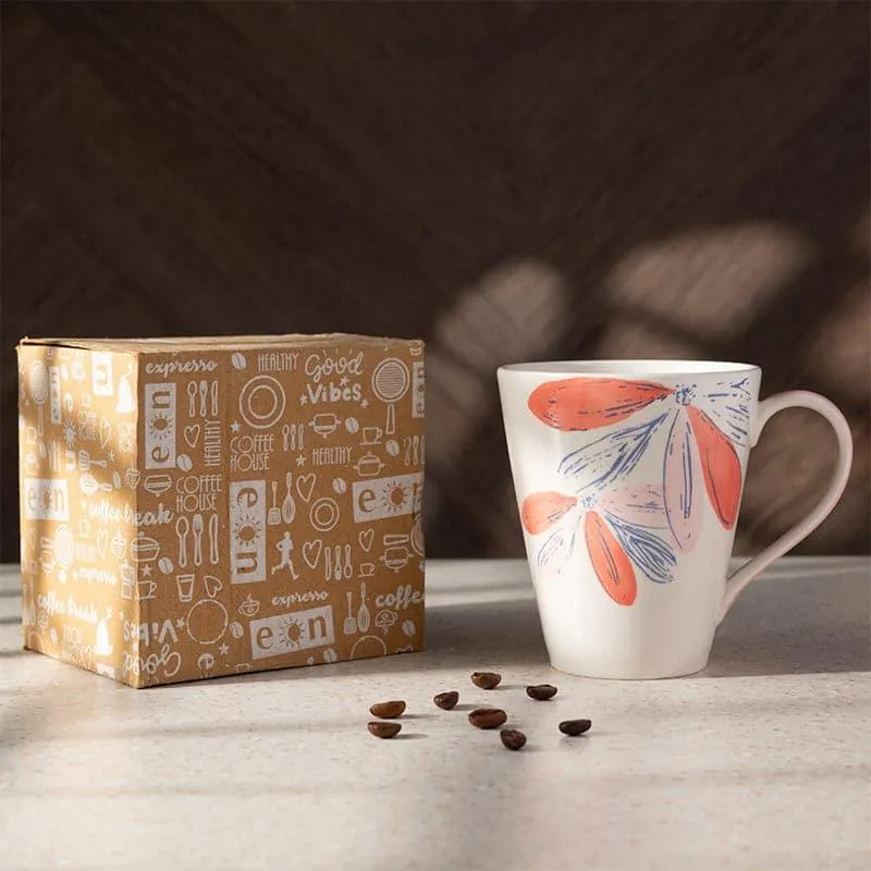 White porcelain mug with coral and blue floral design beside a coffee-themed box